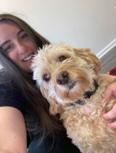 A woman holding onto her dog while sitting on the floor.