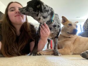 A woman is kissing her dog on the nose.