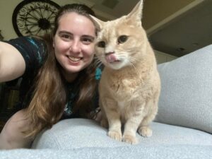 A girl and her cat are posing for the camera.