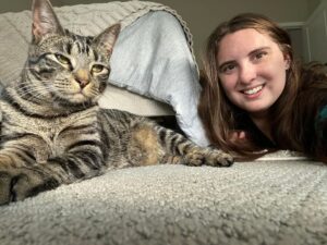 A woman and cat laying on the bed