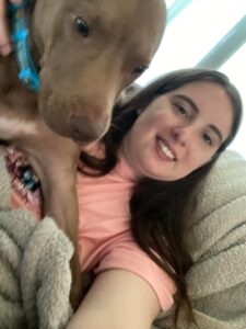 A woman sitting on the couch with her dog.