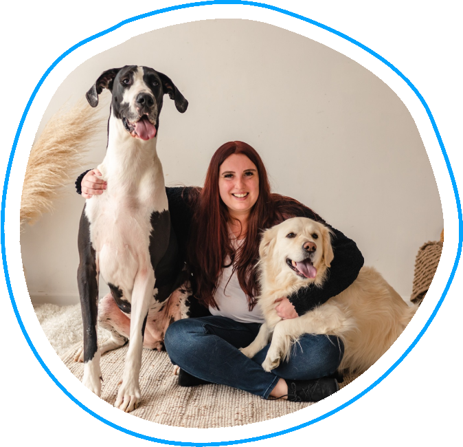 A woman sitting on the ground with two dogs.